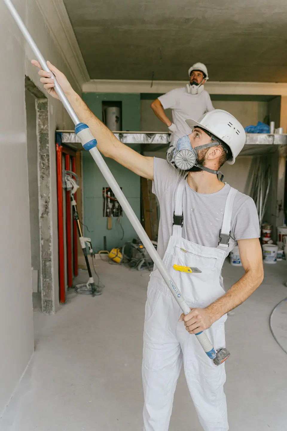 Profissional com capacete, máscara e macacão trabalhando na reforma completa de um interior
